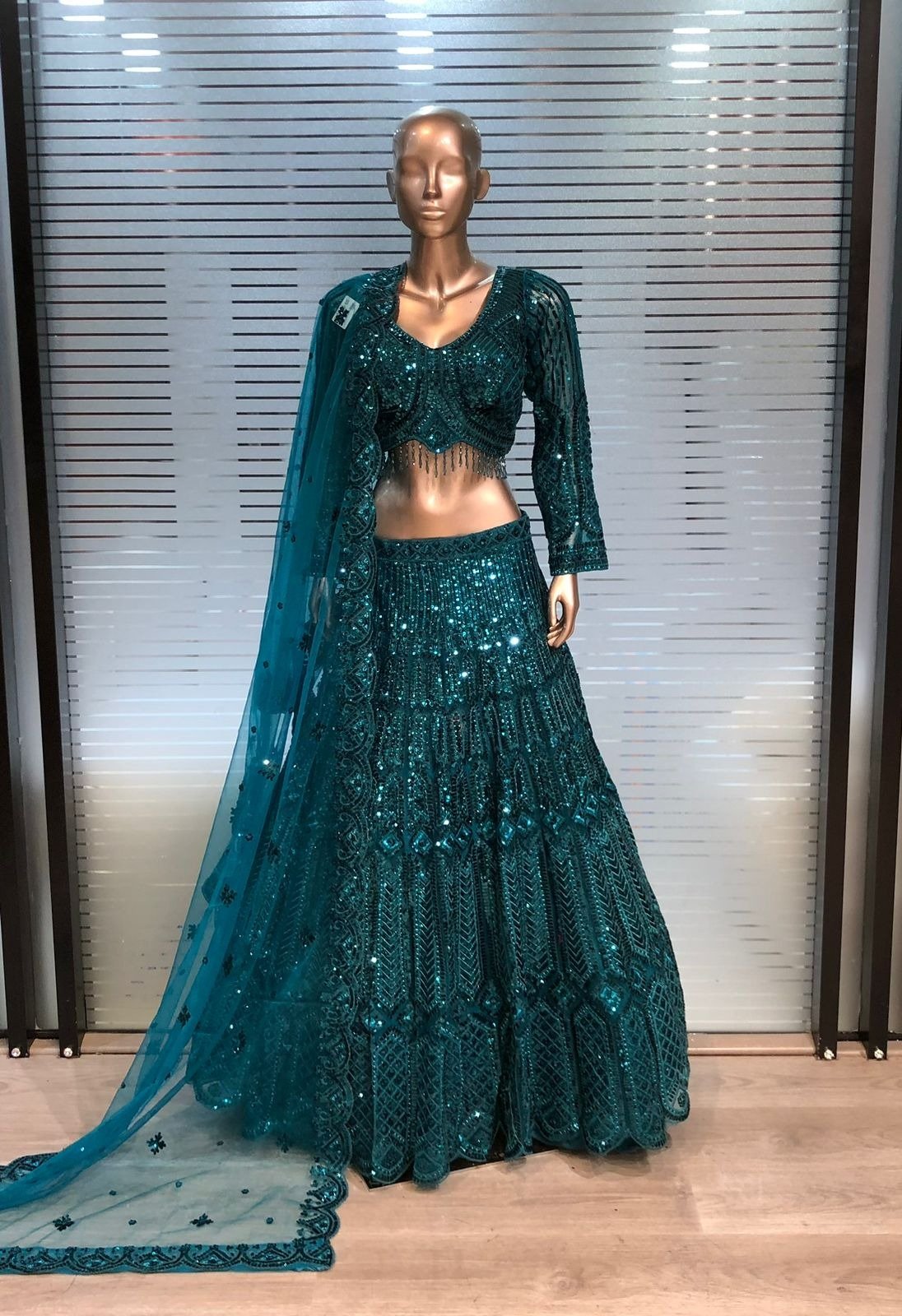 Teal sequin embroidered lehenga set with embellished blouse and matching dupatta displayed at Raunak Boutique